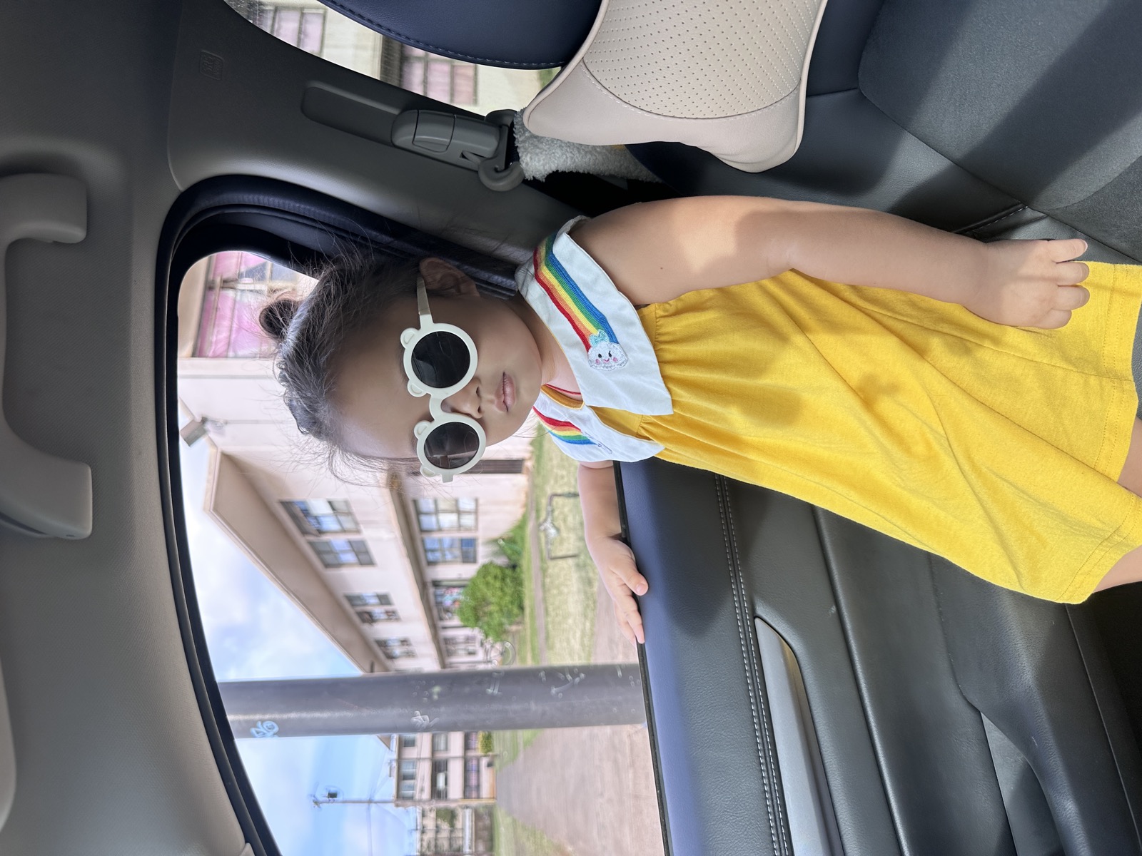 A little girl in sunglasses and a yellow dress on O&rsquo;ahu